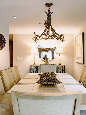 Elegant dining area featuring a rustic chandelier, modern furnishings, and a centerpiece of pinecones, reflecting the cozy mountain charm of RamsHorn Lodge in Vail, Colorado.