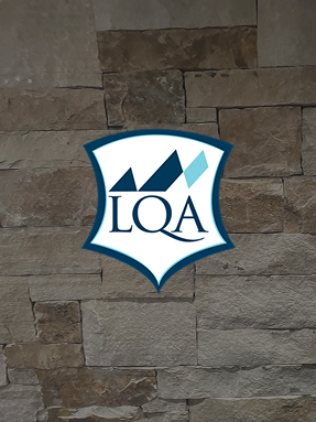 Logo of RamsHorn Lodge featuring "LQA" on a textured stone wall background, representing luxury accommodations in Vail, Colorado.