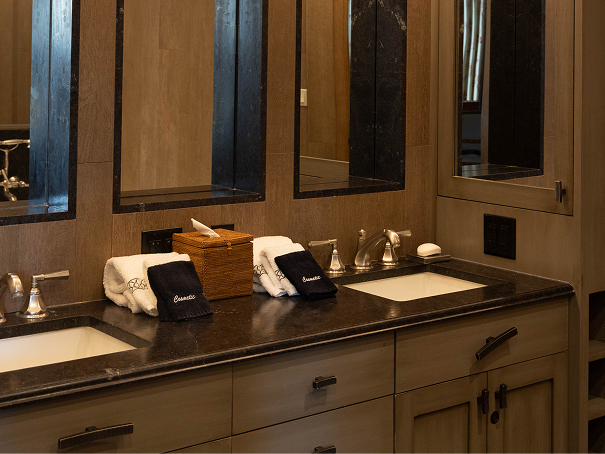 Luxurious bathroom with dual sinks, modern fixtures, and elegant decor, featuring plush towels and a wooden storage box, reflecting the upscale amenities of RamsHorn Lodge in Vail, Colorado.